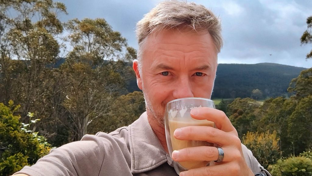 Richard Scott at home, outside in nature, drinking coffee