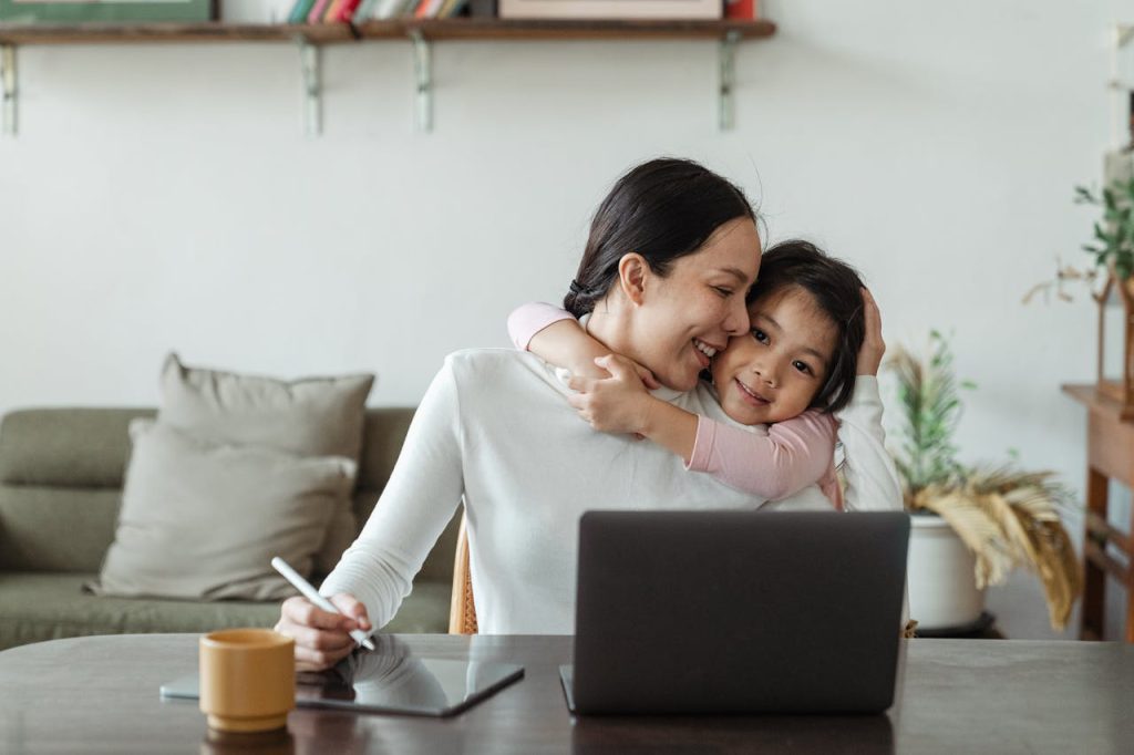 happy working, working from home on computer, at home with daughter snuggling