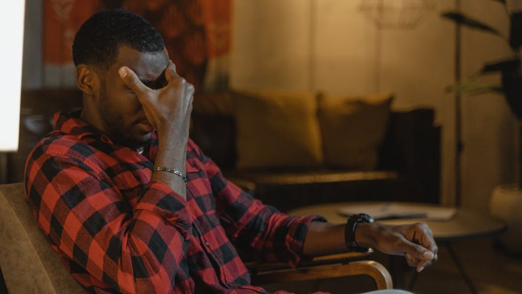 feeling overwhelmed, a man holds his head while suffering anxiety